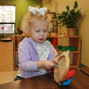 A girl learning how to do needle work at our Montessori school in Roseville, MN-8b5cab436e