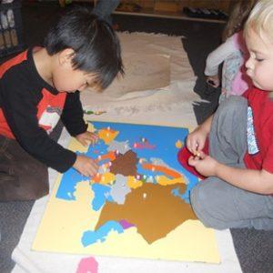 Children using a world map puzzle at our Montessori school in Oakdale, MN-e0476a30d6