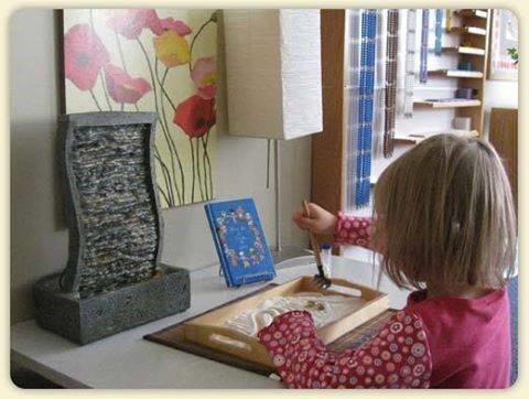 Child playing with a small tabletop zen garden in a peace corner