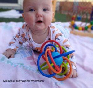 Baby Playing on the Floor with Toy — Minneapolis, MN — Miniapple International Montessori